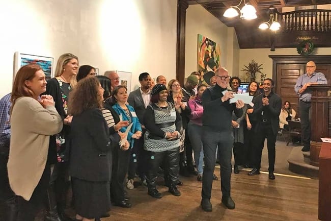 Group of individuals behind a man reading from a piece of paper.