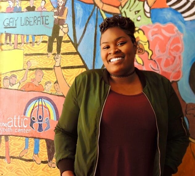 Photo of woman in front of Attic mural.